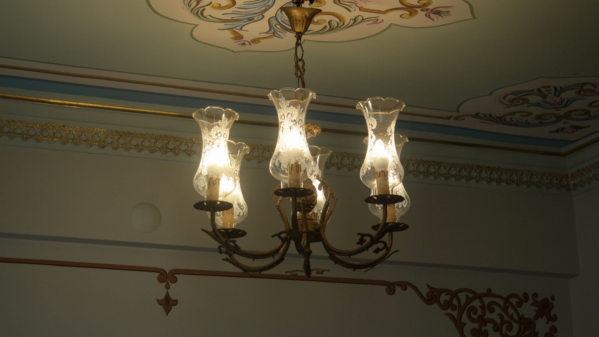 Lampadario antico in ferro battuto e verto attaccato al soffitto